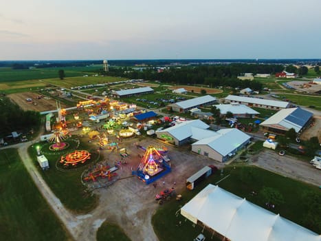 Aerial View of Thriving County Fair in Indiana, Illuminated Carnival Rides Amidst Rural Landscape, 2015