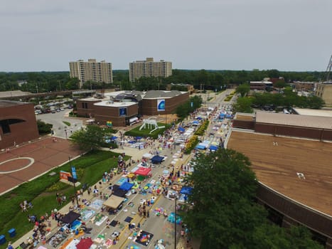 Aerial view of Three Rivers Festival in Downtown Fort Wayne, bustling with colorful stalls and a lively crowd, urban setting.