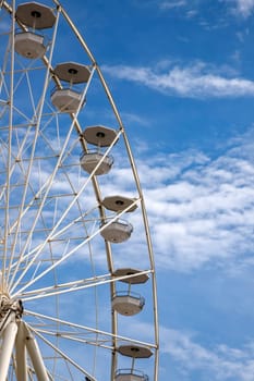 A part of the Ferris wheel against a cloudy blue sky