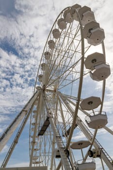 A part of the Ferris wheel against a cloudy blue sky