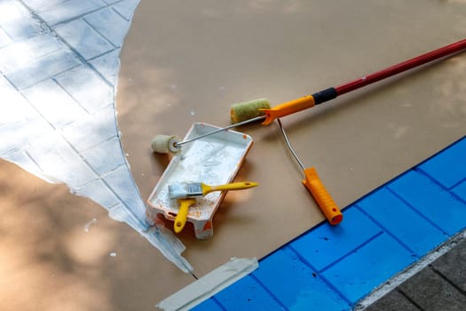 Painting roller, brushes, and a plastic tool to paint outdoors.