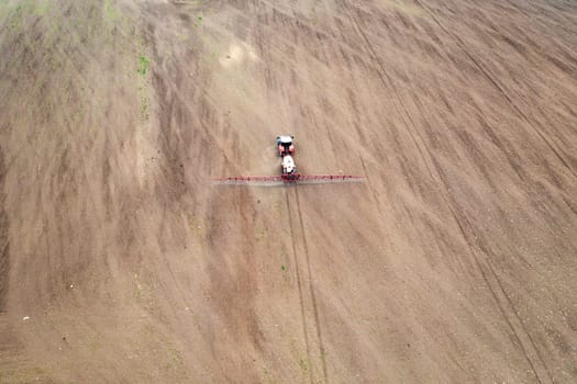Aerial view of tractor spraying aerosol on a grain fields