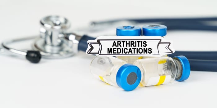 Medical concept. On the table there is a stethoscope, injections and a sign with the inscription - Arthritis medications