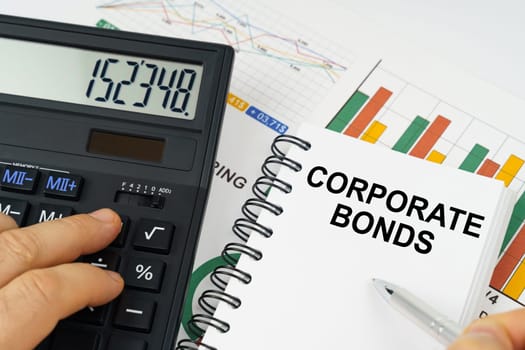 Business concept. On the table there is a calculator, reports with graphs and a notepad with the inscription - Corporate Bonds