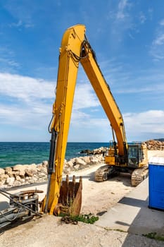 Big excavator working at the construction site near the sea