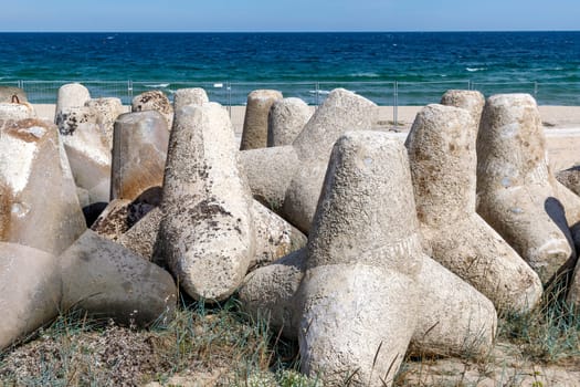 A breakwater made of concrete structures of tetrapods, installed on the coast.