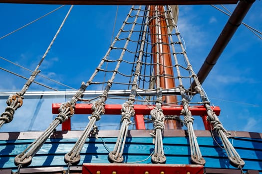 Part of an old wooden ship with ropes tied in knots and wooden fasteners.