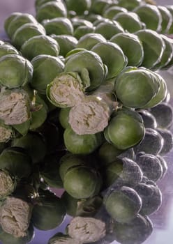 Fresh raw organic green brussel sprouts on stalks on Reflection black background with Natural sunlight. Brussel Sprouts Groninger vegetable, Uncooked Rosenkaal Brussel sprouts, Space for text, Selective focus.