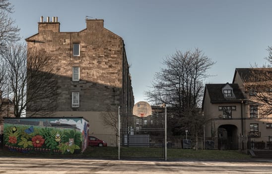 Edinburgh, Scotland, Jan 17, 2024 - Basketball backboard with the orange hoop metal ring at outdoor basketball courts in the park against old buildings background in the city downtown. Space for text, Selective focus.