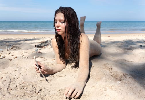 Youth, beauty, healthy lifestyle and nudity. Young fully naked woman with body covered with sand on the sea coast on a sunny day.