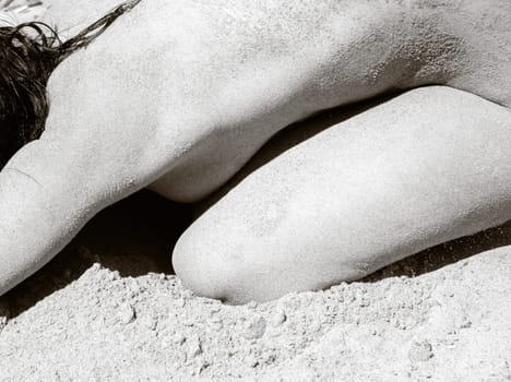 Youth, beauty, healthy lifestyle and nudity. Young fully naked woman with body covered with sand on the sea coast on a sunny day.