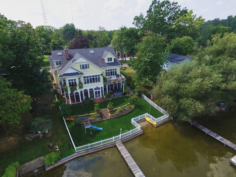 Luxurious waterfront home in Syracuse, Indiana, showcasing elegant architecture and design, featuring a manicured lawn, private dock, and lively social gathering, 2015
