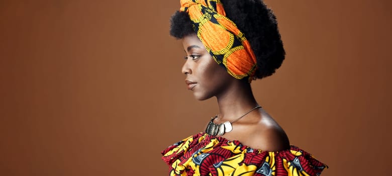 Culture, African fashion or face of black woman in studio on a brown background for trendy style. Unique, beauty or model with confidence, pride or afro posing in wrap, clothes or traditional outfit.