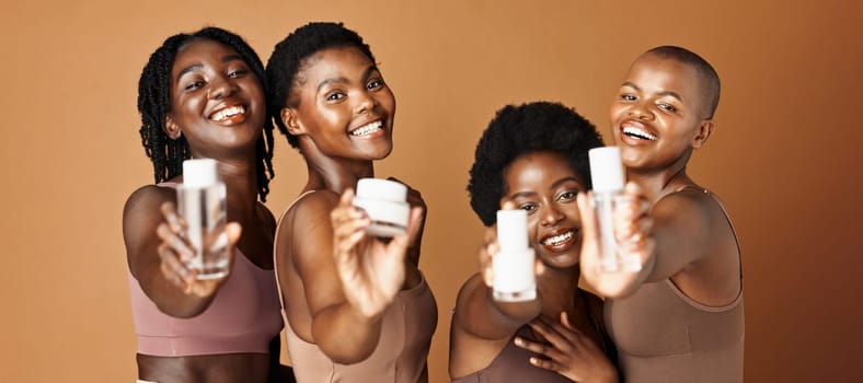 Happy black woman, skincare and beauty products for tone or foundation against a brown studio background. Group portrait of African female people or model smile together with skin makeup on mockup.