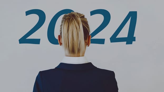 business woman with the new year 2024 . Businesswoman look at 2024 blue color letter over grey background, Business happy new year 2024 cover concept. High quality image