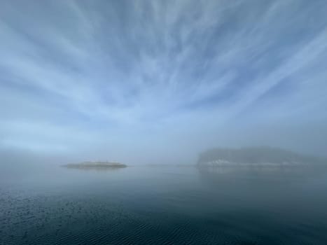 Scenic view of islands in fog near Stryker Island, British Columbia. Islands and blue, cloudy skies reflecting on the water.