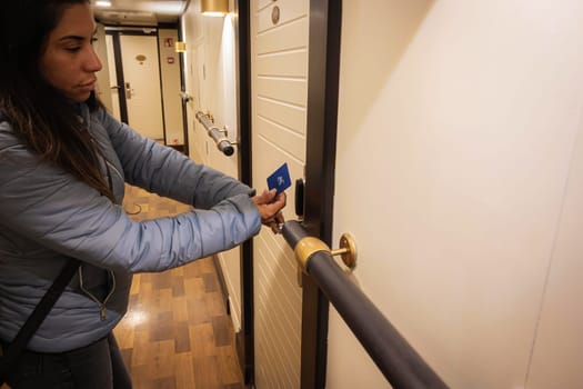 Beautiful latin woman using a proximity card to unlock the hotel room door. Digital or keyless to authenticate. Wireless technology