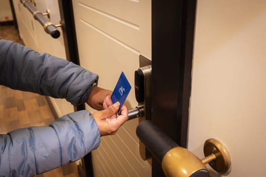 Closeup hand of young latin woman using a keycard to unlock electronic sensor of hotel door. Security concept