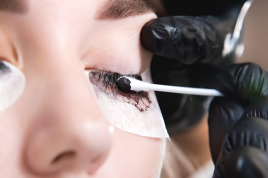 A makeup artist performs the procedure of lamination and coloring of eyelashes on a beautiful woman in a beauty salon. Eyelash extensions. Client and master, beauty procedures