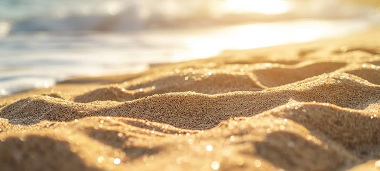 Close-up of sparkling golden sand texture with soft sunset light casting shadows.