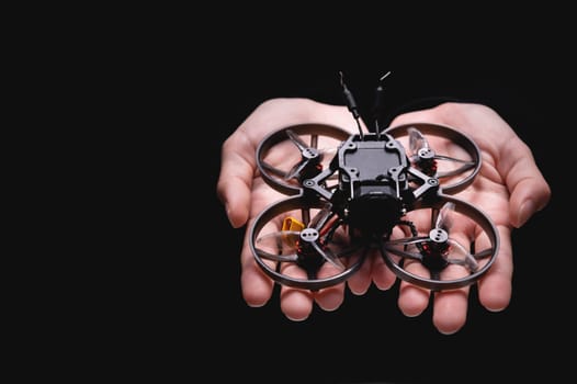 A woman holds a racing drone in her hands, showing it to the camera on her palm. Close-up of a hobby toy.