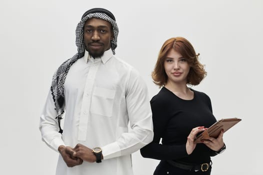 Arabic entrepreneur and a businesswoman, exuding confidence and unity, pose together against a clean white backdrop, symbolizing a dynamic partnership characterized by ambition, innovation, and collaborative success in the business realm.