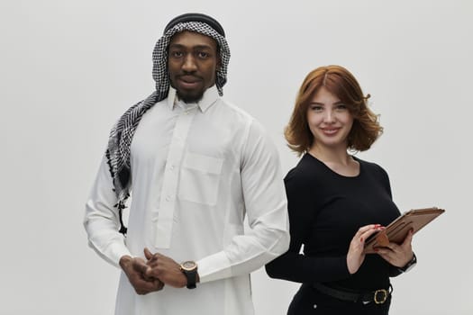 Arabic entrepreneur and a businesswoman, exuding confidence and unity, pose together against a clean white backdrop, symbolizing a dynamic partnership characterized by ambition, innovation, and collaborative success in the business realm.