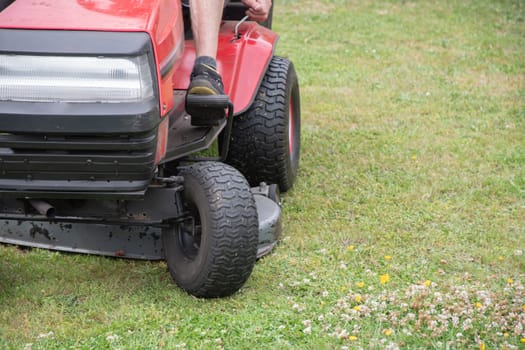 Lawn mower mows the grass, a middle-aged male gardener works on a mini tractor in the garden, rotary, High Quality Photo