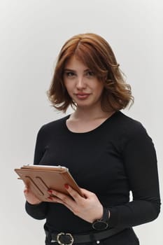 In a powerful display of modern professionalism, a confident red-haired businesswoman strikes a pose with a tablet against a clean white background, embodying ambition, innovation, and corporate charisma in the contemporary business landscape.
