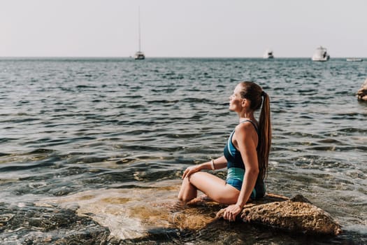 Woman beach vacation photo. A happy tourist in a blue bikini enjoying the scenic view of the sea and volcanic mountains while taking pictures to capture the memories of her travel adventure