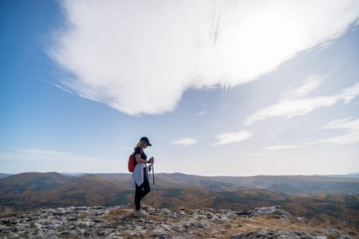 woman on mountain peak looking in beautiful mountain valley in autumn. Landscape with sporty young woman, blu sky in fall. Hiking. Nature.