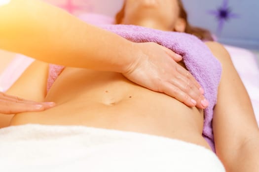 Top view of hands massaging female abdomen.Therapist applying pressure on belly. Woman receiving massage at spa salon.