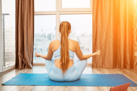 Young woman meditating at home. Girl practicing yoga in class. Relaxation at home, body care, balance, healthy lifestyle, meditation, mindfulness, recreation, workout, fitness, training concept.