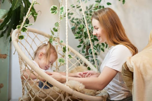 Happy loving family. Mother and daughter child girl playing and hugging in living room with wicker chair