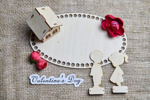 Wooden figurines of a couple, a house and the inscription Valentine's Day. The concept of a holiday of love and lovers. Background, texture, place for text and copy space