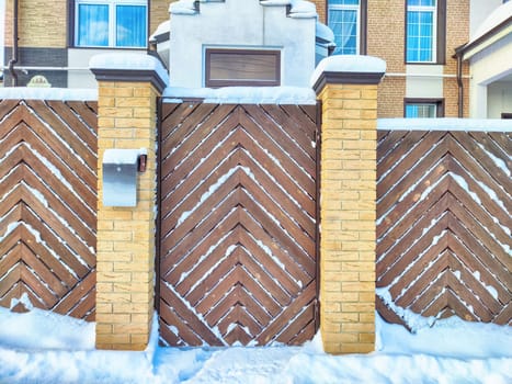 New gate, entrance to a private territory on a winter day and snow. Metallic texture and background. Fence