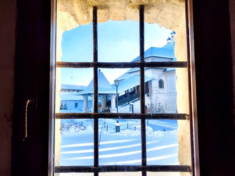 View of the street and the building through the metal grating, grill on window in winter with snow. Abstract Background, pattern, frame