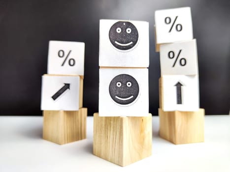 Wooden cubes in a column and row with white signs with a smiley sign, an arrow, a percentage. The concept of positivism. Positive thinking leads to the achievement of results and profits