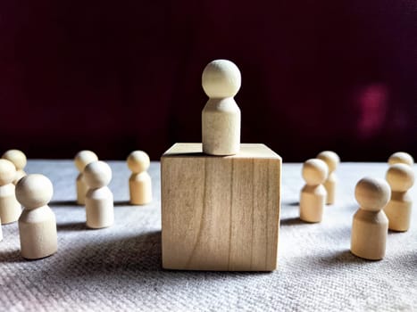 Wooden toy doll on high pedestal and many other figures below. Concept of leadership, which is not available to everyone. Victory and the winner. Talent, Recruitment employee and Successful business