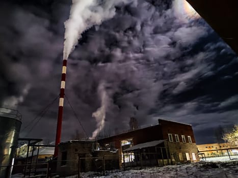 Winter night industrial landscape. Coal-fired power station with smoking chimneys against dramatic dark sky. Carbon dioxide CO2 emissions as primary driver of global climate change. Air pollution