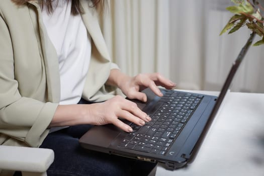The hands of an elderly woman on a laptop keyboard. The lady communicates, works, studies on the Internet online. A businesslike old lady in a modern gadget