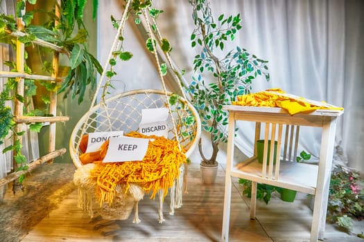 Signs with the words keep, donate, discard and fashion clothes folded in stacks in cozy room. The concept of cluttering and decluttering. Background