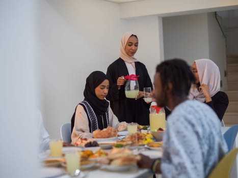 A diverse Islamic family gathers for iftar, joyfully breaking their fast together during Ramadan, with a Muslim woman in a beautiful hijab gracefully pouring water to mark the end of their fast, showcasing the unity, love, and spiritual connection that define this special family moment.