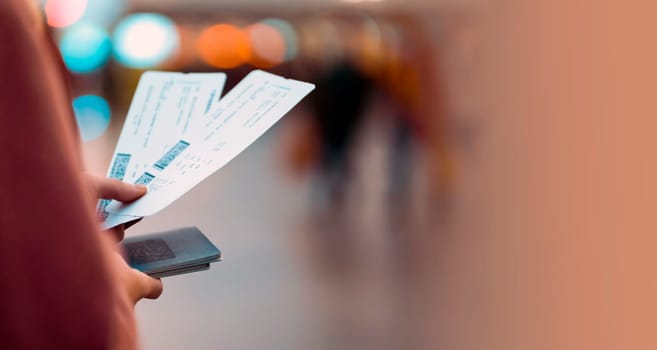 A young girl is going on a trip, holds plane tickets in her hands and goes to check-in, boarding a flight, close-up view of a boarding pass on a blurred background.