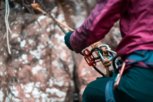 Climbing equipment, ropes, carabiners, harness, belay, close-up of a rock-climber put on by a girl, the traveler leads an active lifestyle and is engaged in mountaineering.