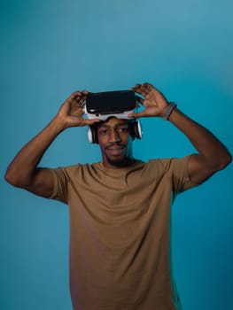 In a futuristic visual, an African American man stands isolated against a striking blue backdrop, adorned with VR glasses that transport him into a cutting-edge virtual reality experience, merging technology and innovation in a contemporary display.