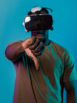 African American man, wearing virtual reality glasses, expresses dissatisfaction by pointing down with his hand while standing isolated against a blue background, portraying a modern critique within the immersive digital realm.