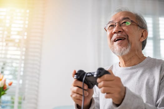 Asian mature man hands using game controller play videogame, Funny on retirement elderly smile sitting on sofa life gaming, senior old man enjoying holding joystick playing video game at home