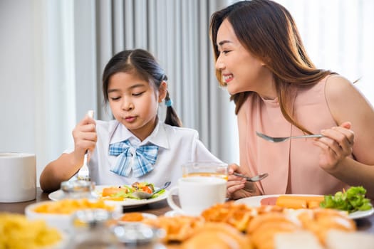 Family breakfast. Mom and little preschooler have fun smile eating meal together, Asian mother and child daughter having breakfast on food table, Healthy food at home in morning before go to school