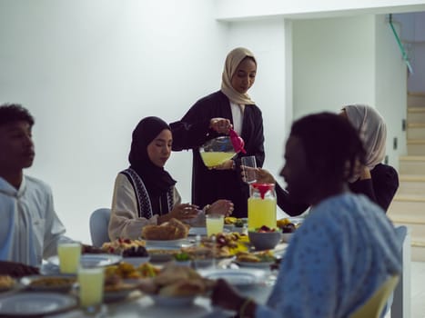 A diverse Islamic family gathers for iftar, joyfully breaking their fast together during Ramadan, with a Muslim woman in a beautiful hijab gracefully pouring water to mark the end of their fast, showcasing the unity, love, and spiritual connection that define this special family moment.